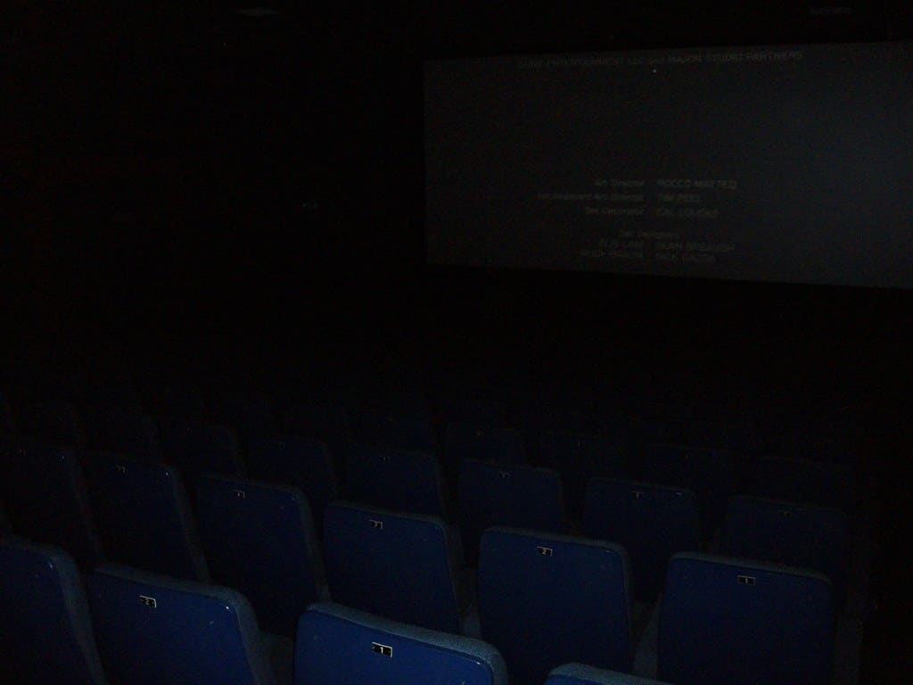 Pusta sala kinowa z napisami końcowymi na ekranie — źródło wyobrażeń o hipnozie